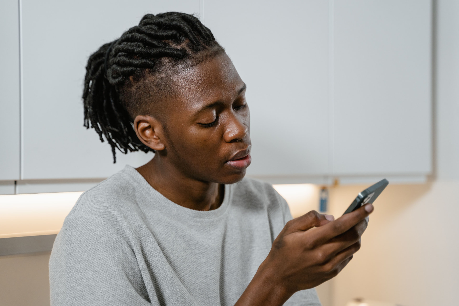 A young person with braided hair using a phone to understand a health concern and find care